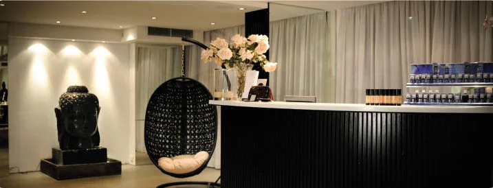 You Day Spa reception — curved black-slatted counter, roses and Buddha head